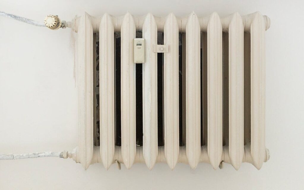 Beli radijator sa termostatom na zidu